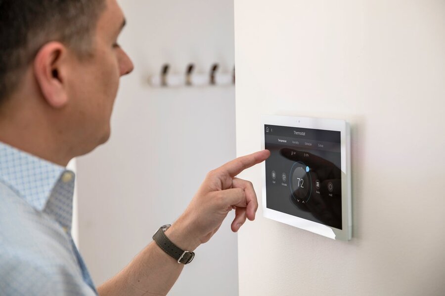 A man using a Control4 touch screen interface mounted to the wall.
